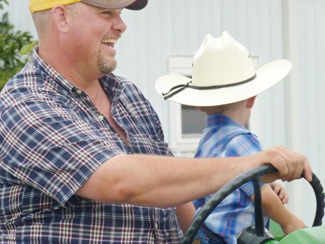 Close-up of driver and rider on vintage John Deere Tractor in Monday's parade at the fair
